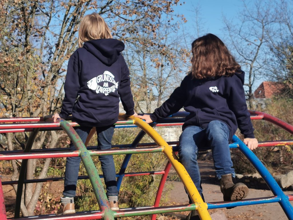 Kinder auf Klettergerüst mit Kleidung Logo Schule