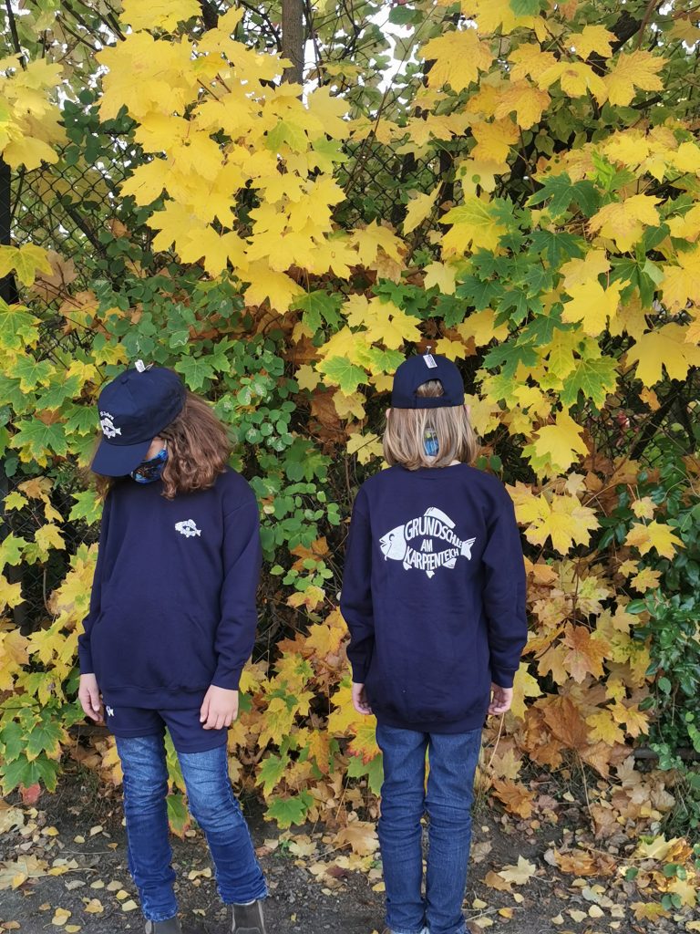Zwei Kinder tragen Sweatshirts mit Logo.